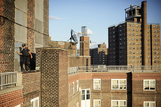 A rookie officer makes her way along a narrow ledge between two office buildings. Bolfo explains that officers looking for drug dealers "sneak around the exterior of buildings because they don't want to go in the front door."