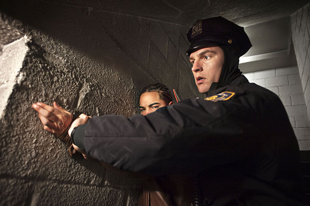 An officer detains a suspect inside a stairwell.