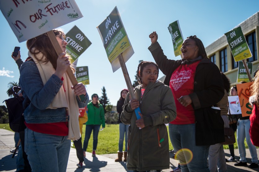 Magdaline Armstrong (right), a first-grade teacher, and her daughter Nilaya, eight, rally on a picket line with kindergarten teacher Grace Allen (left) outside Futures Elementary School.