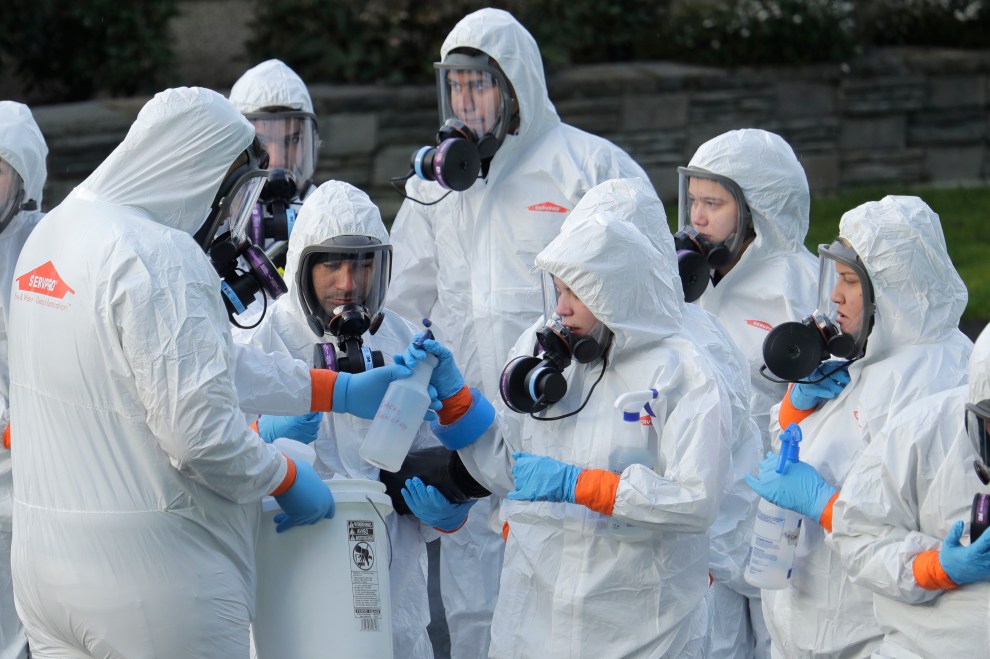 Workers from a Servpro disaster recovery team wearing protective suits and respirators are given supplies as they line up before entering the Life Care Center in Kirkland, Wash., March 11, 2020. 