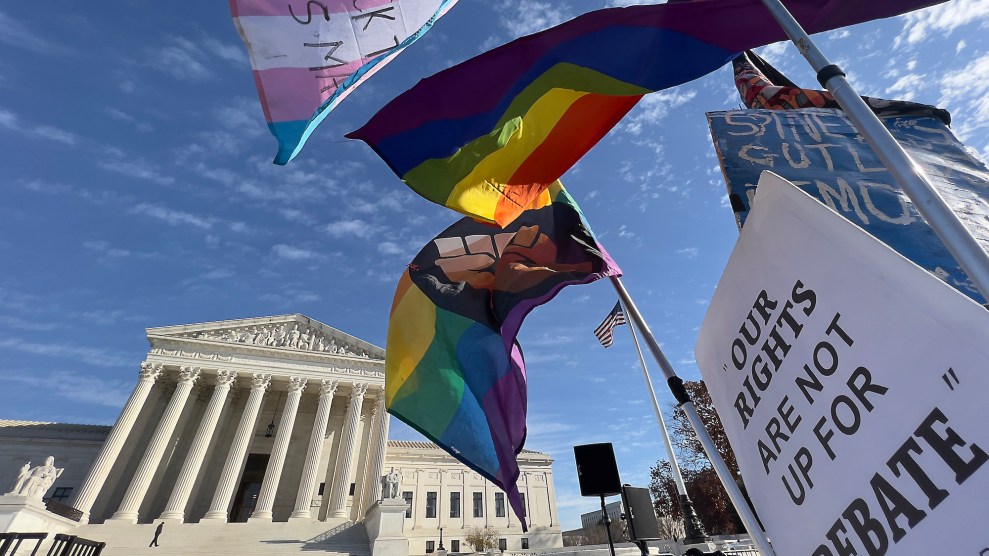 Pride and transgender flags fly at a protest outside the Supreme Court. A sign reads, "Our rights are not up for DEBATE."
