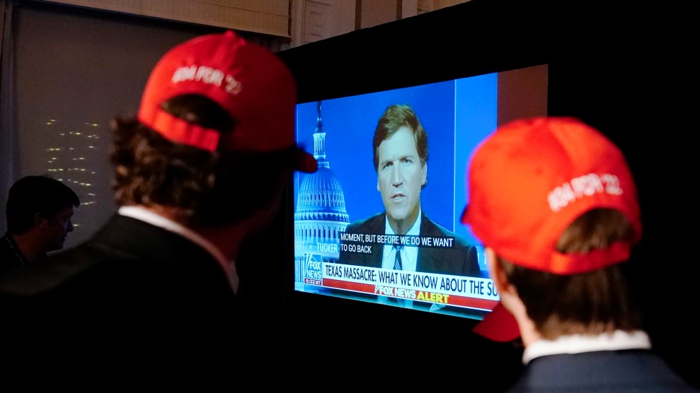 Two men in red hats watch Tucker Carlson's Fox News show on TV.