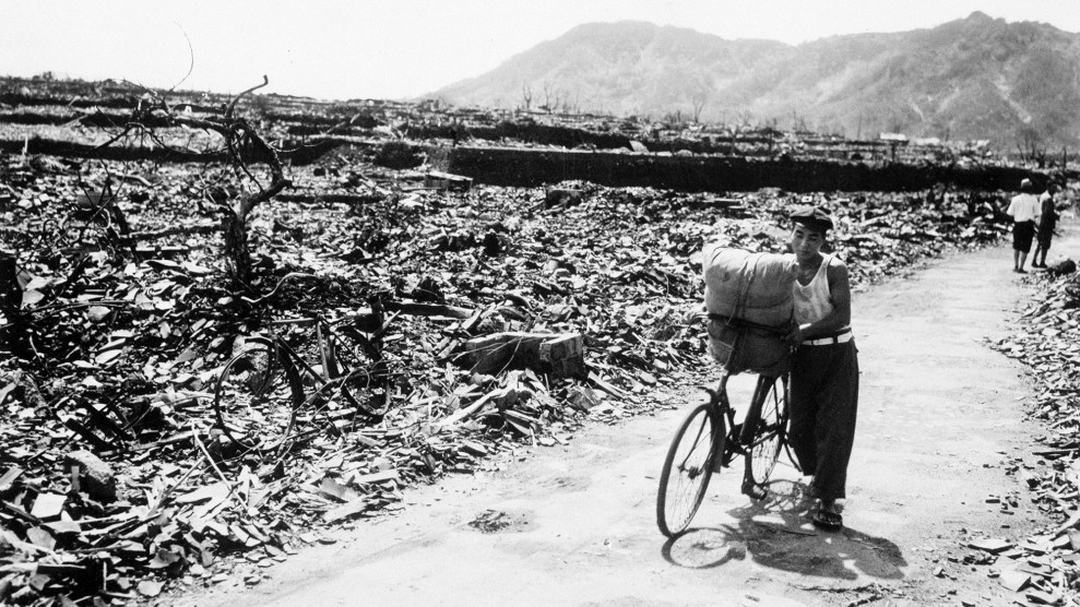 A man pushes a loaded bicycle down a cleared path in a flattened area of Nagasaki.