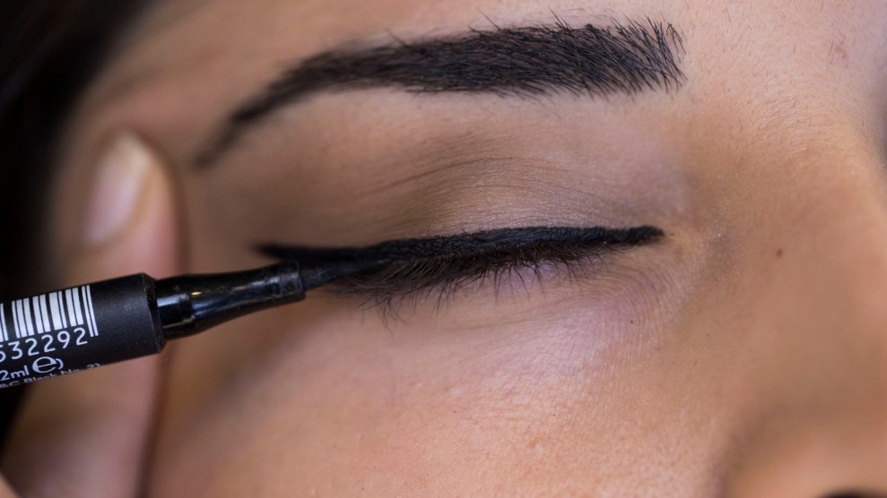 A close-up photo of a closed eye. Black-winged eyeliner is being applied.