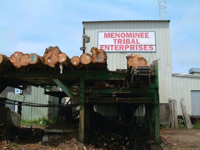 The Menominee Tribal Enterprises sawmill, with logs in front of the building
