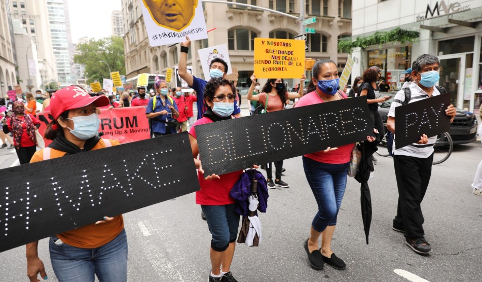 People participate in a "March on Billionaires" event on July 17, 2020 in New York City. Four people hold up signs that say "#Make Billionaires Pay"