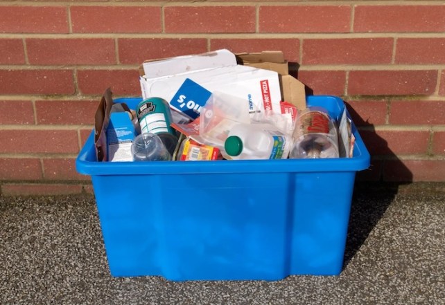 A recycling box with mixed plastic waste, among other materials.