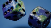 A set of dice roll on a blue background. The die are covered with an Earth-like print, evoking that they may be the globe.