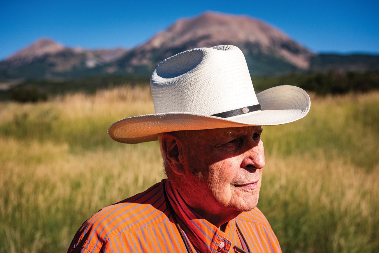 rancher in cowboy hat standing outside.