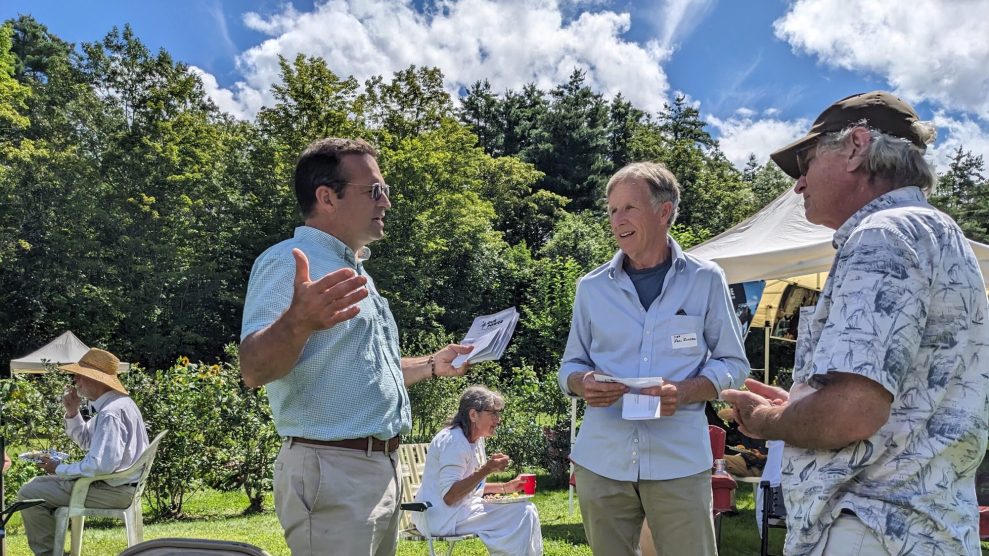 Seth Berry, an author of the Pine Tree Power ballot proposal that would replace the state's investor-owned utilities with a nonprofit one, chats with voters at a gathering of climate activists in Winslow, Maine, in August 2023.