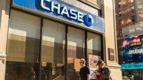 Two white individuals walk in front of a building with the label "Chase" on it.