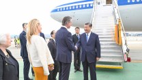 Xi Jinping shaking hands with Gov. Gavin Newsom, with a plane behind him.