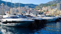 A tight shot of some clearly expensive boats at the Monaco Yacht show in Monte Carlo, September 27, 2023, from the water side, with shoreline buildings and hills in the backdrop.