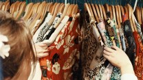 A person going through an assortment of clothing with different patterns on a rack.