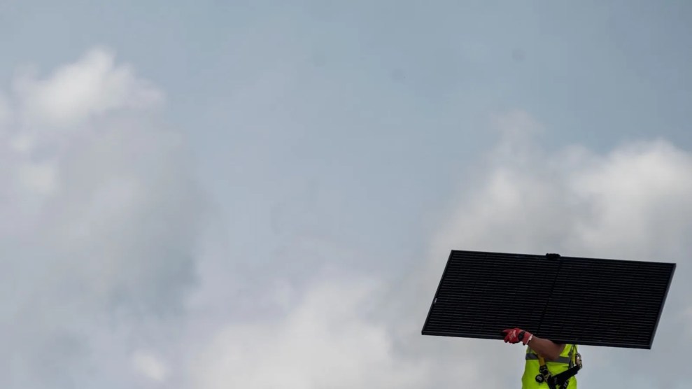 A person carrying a solar panel, which is blocking their face, with cloudy skies in the background