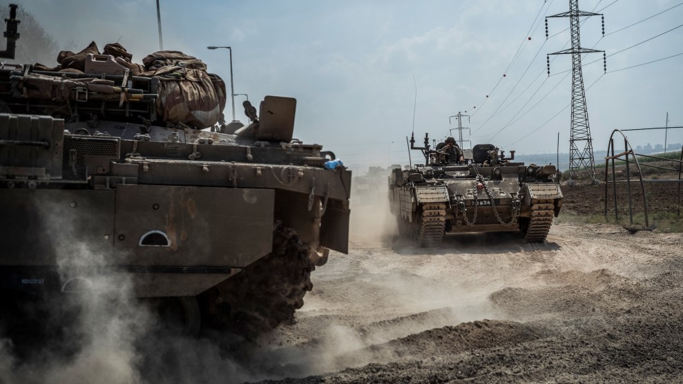 Two combat tanks near each other which are a dark brown or dark gray color with dust surrounding them