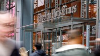 Front of New York Times building with people blurred walking by.