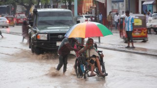 A Somali woman is pulled on a wheelchair through a street filled with water
