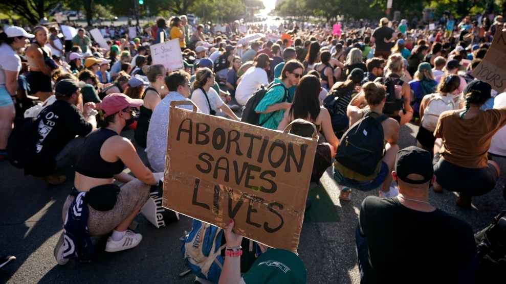 Protestors sit on the streets of Austin, Texas after the Supreme Court's decision to overturn Roe v. Wade. One protestor holds a sign reading "Abortion Saves Lives."