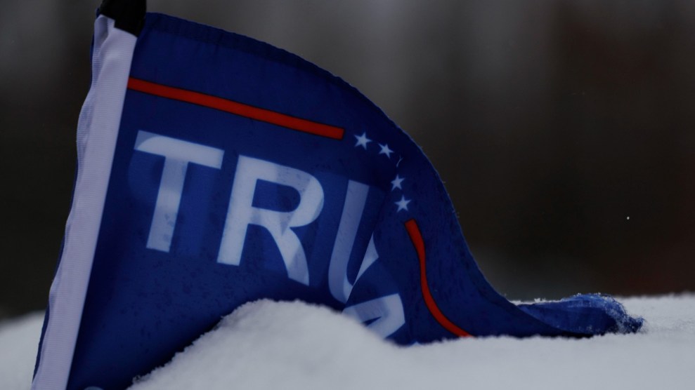 A dark blue Trump flag is buried in the snow