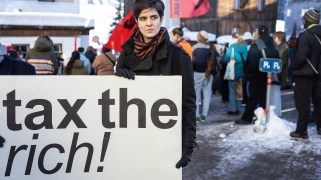German-Austrian millionaire heiress Marlene Engelhorn holds a sign reading ''tax the rich!'' during a rally at the World Economic Forum in Davos.