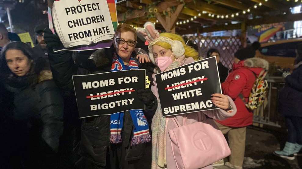 Two protesters holding signs against Moms for Liberty.