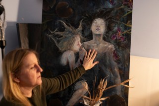 Woman with outstretched hand touching a painting.