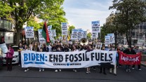 Protesters on a street with signs that say "Biden: End Fossil Fuels"