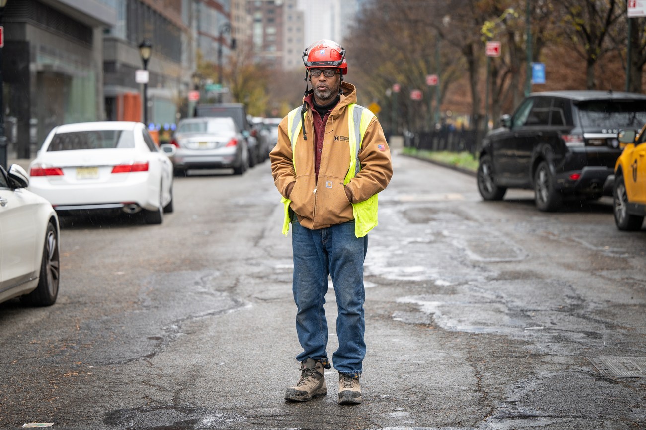 Portrait of a man in a hard hat standing in the street.