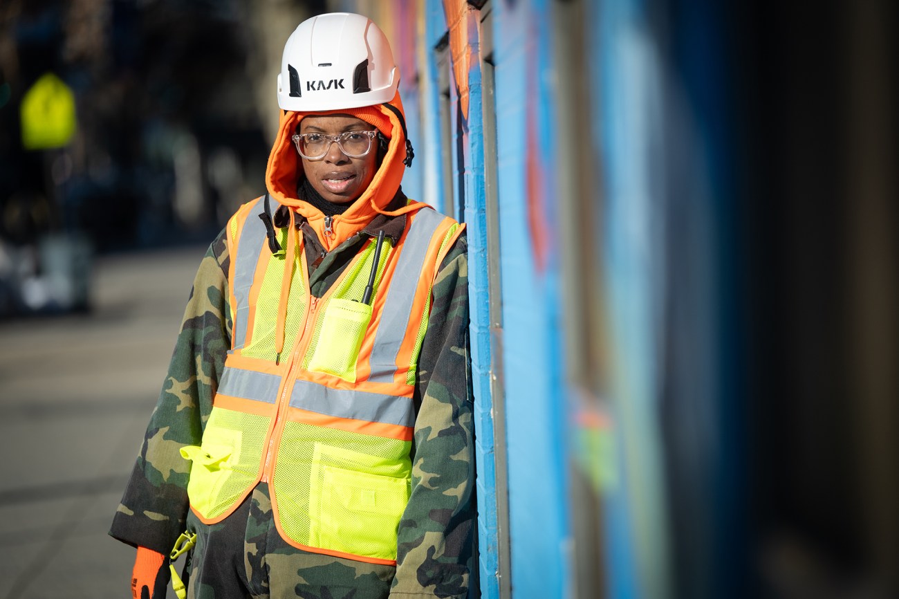 Portrait of a woman with a hard hat in a yellow vest worn over a camo jacket.