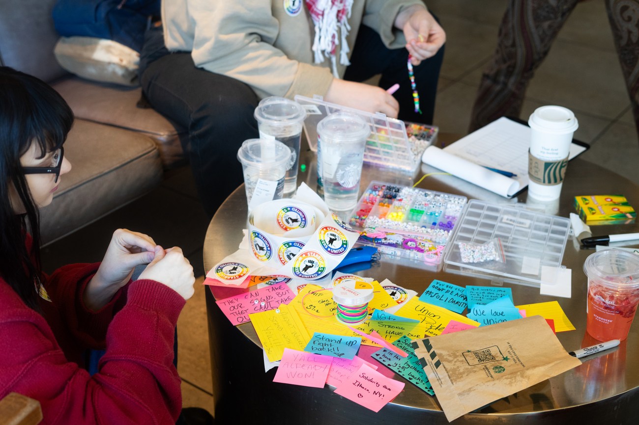 Table with stickers, post-it notes and bead-making materials.