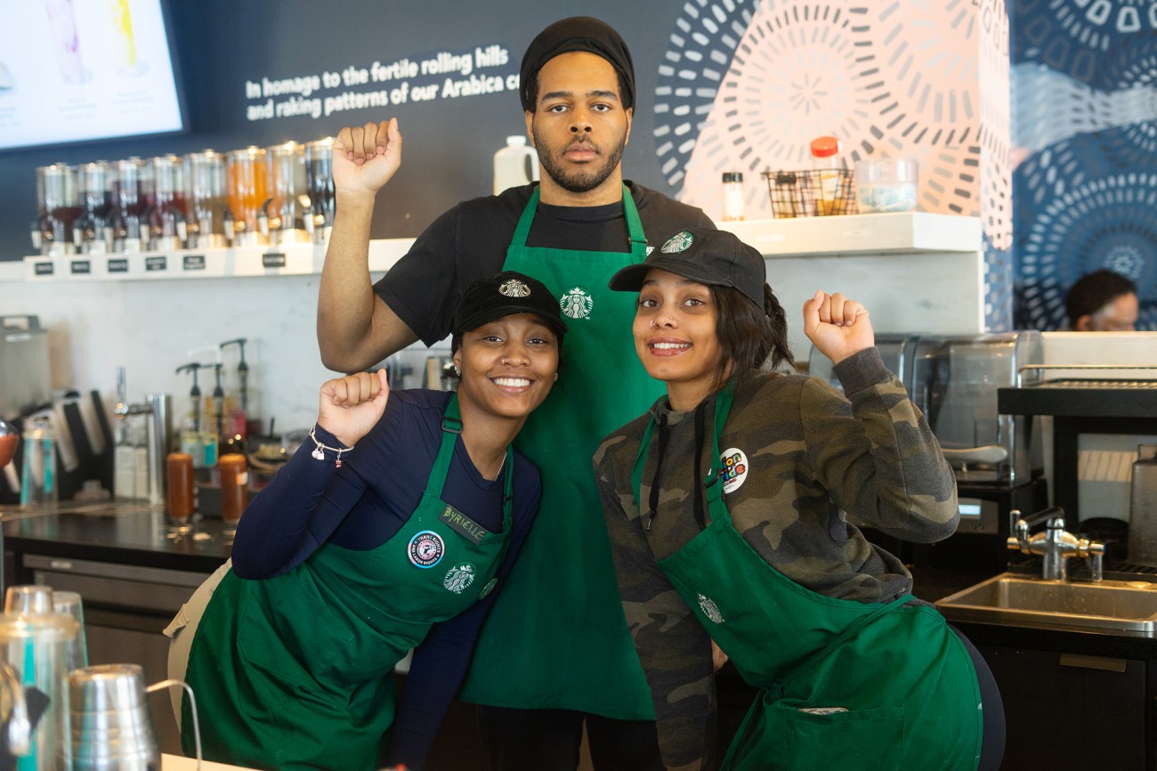 Portrait of three Starbucks employees with raised fists.