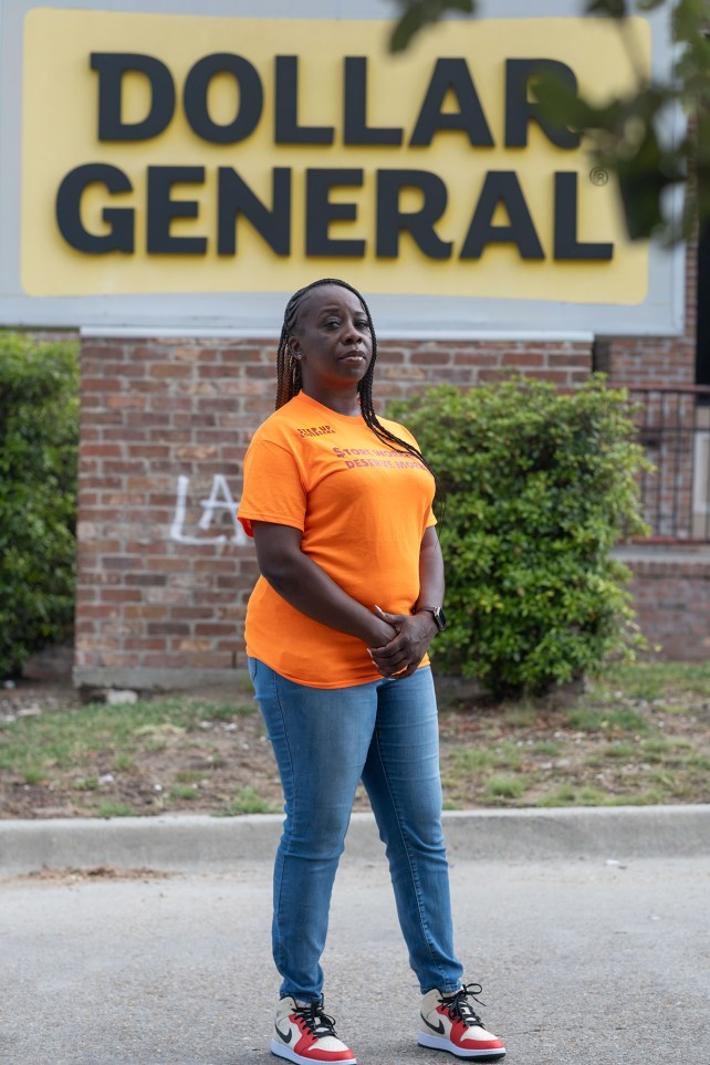 Portrait of a woman in an orange t-shirt standing in front a Dollar General store.