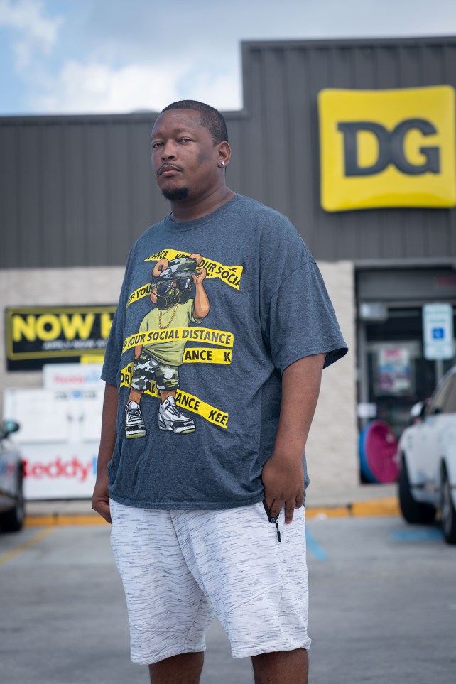 Protrait of a man standing in the parking lot of a Dollar General store.