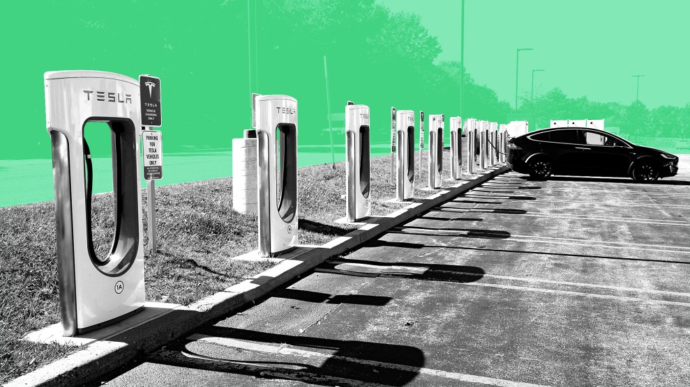 A stylized photograph of a parking lot with electric vehicle charging stations. The stations are elevated making them inaccessible. The EV stations are colored black and white and the background has a green color treatment.