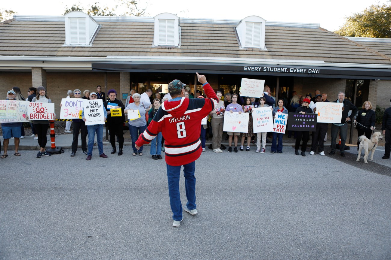 Man in a red hockey shirt yells at a group of protesters.