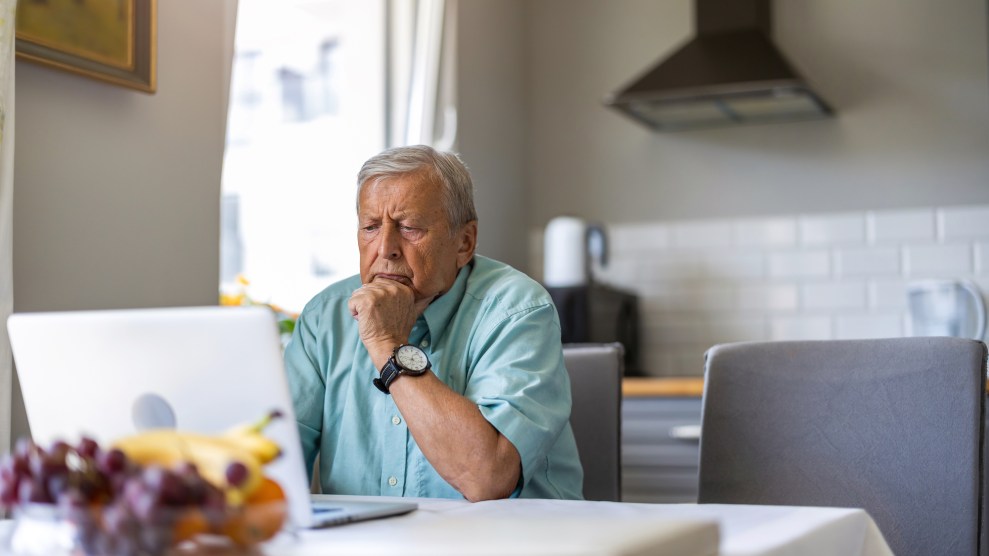 Aging white man using laptop at kitchen table