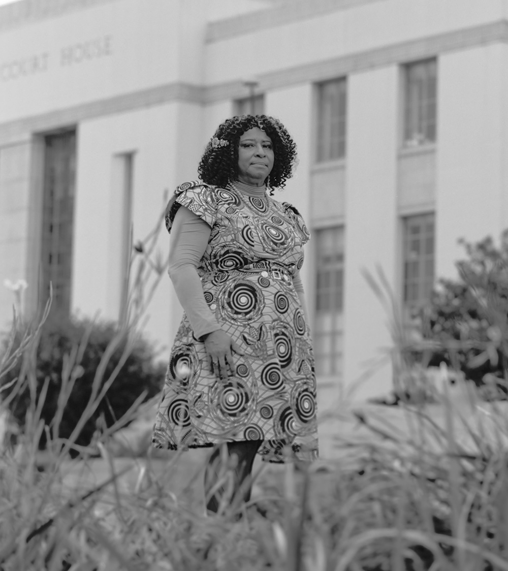 Black and white portrait of a woman standing in front of a courthouse.