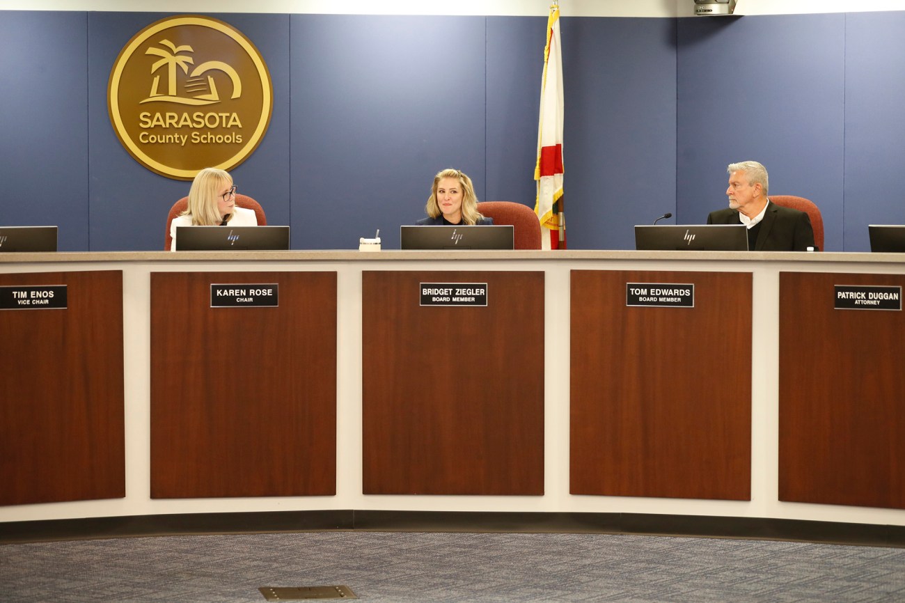 Three school board members – two women and one man – sit during a meeting.