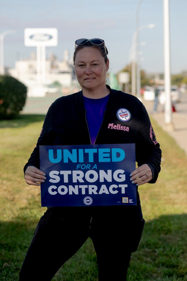 Portrait of a woman holding a UAW strike poster.