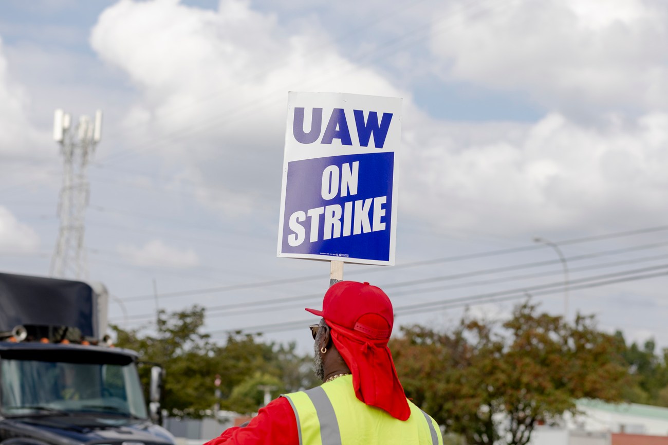 Man in red hat holding a sign that reads "UAW on Strike."