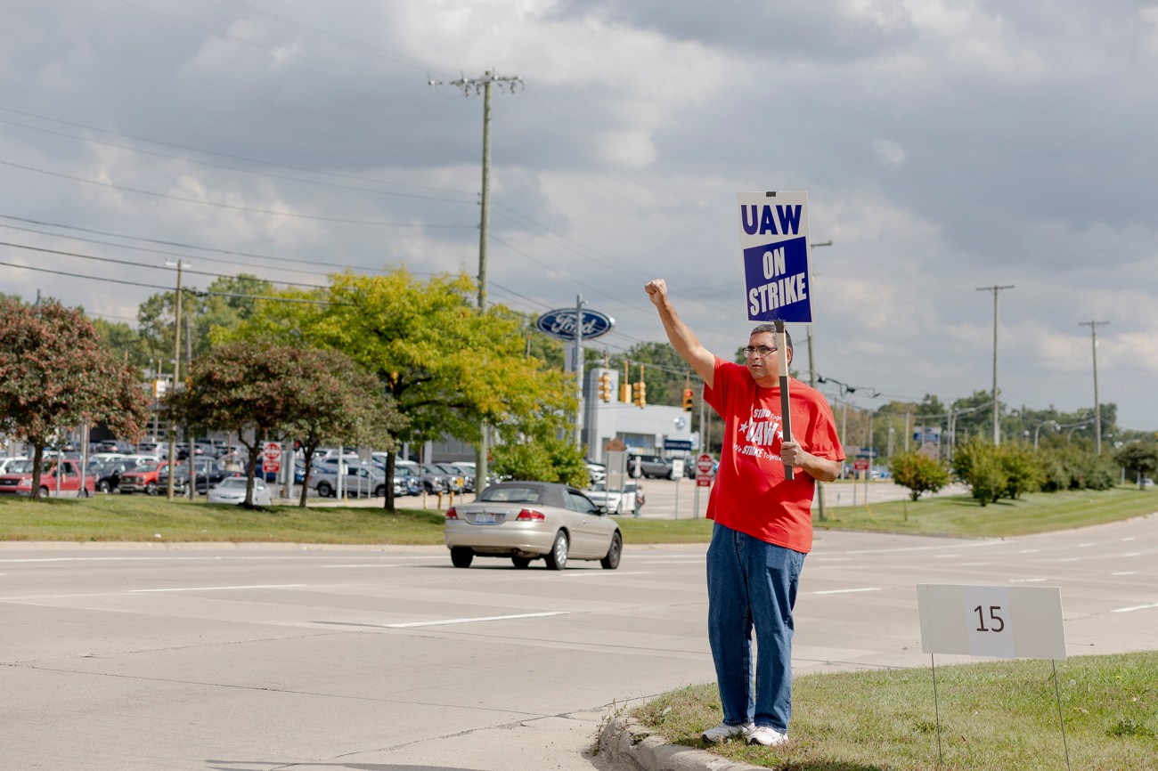 Man holding a UAW strike sign with raised fist.
