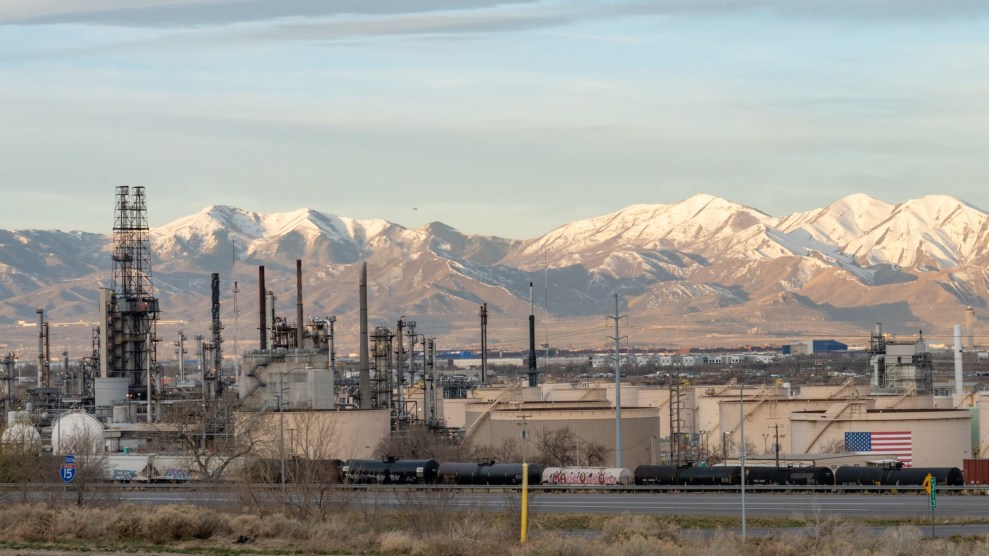 White-capped mountains tower above an oil refinery with an American flag painted on it.