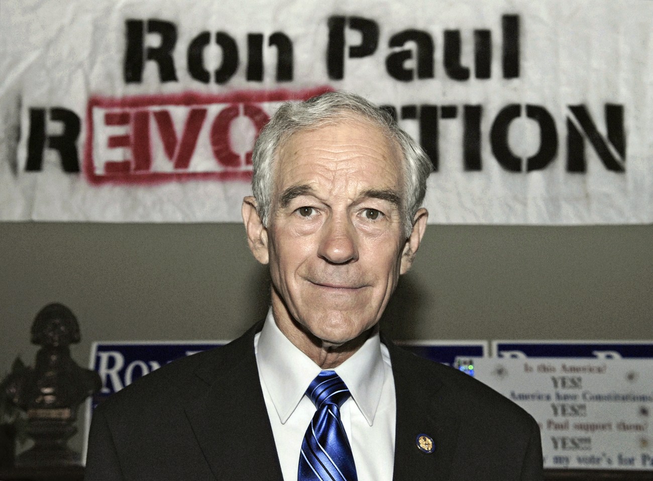 Ron Paul standing in front of a Ron Paul Revolution banner.