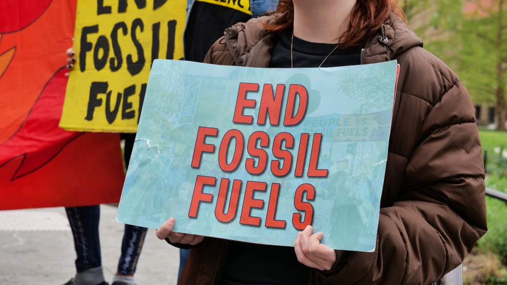 A person, whose head isn't visible, holding up a poster that says "End Fossil Fuels"