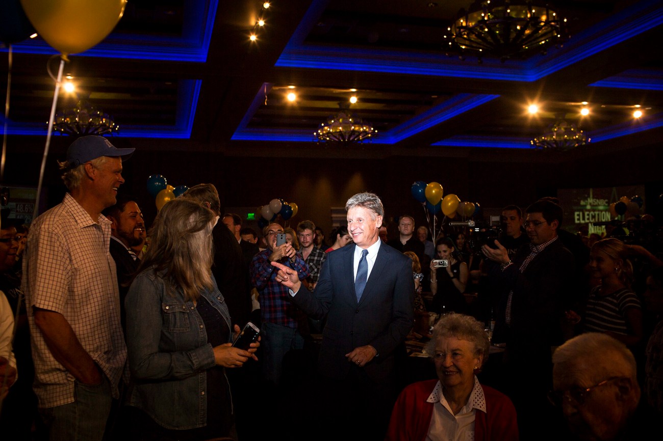 Smiling man surrounded by people at an election night party.