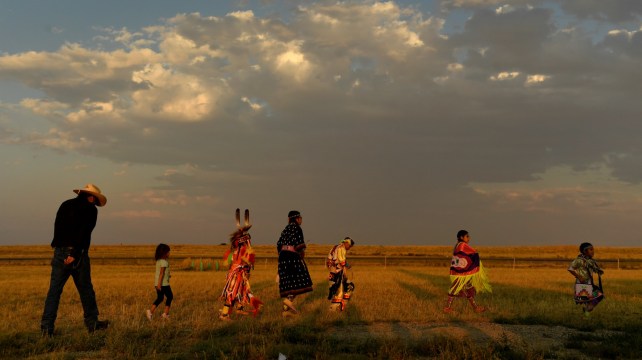 A collection of people walks through an open plain.