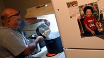 An older Black man pouring water into a boiling pan in a kitchen