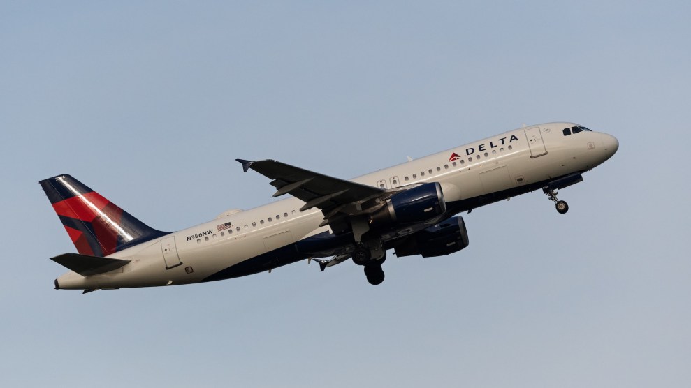 Delta airplane that is airborne with a light blue sky behind it.