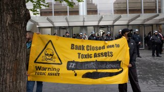 Protestors with a yellow banner that says "Bank Closed Due to Toxic Assets. #ClimateShutdown"